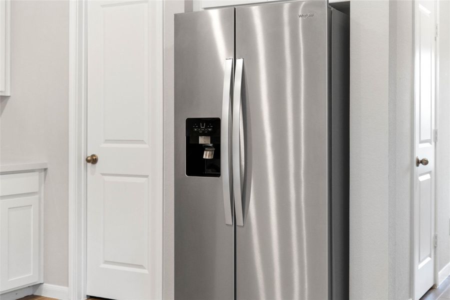 Kitchen comes equipped with a side-by-side Whirlpool refrigerator.
