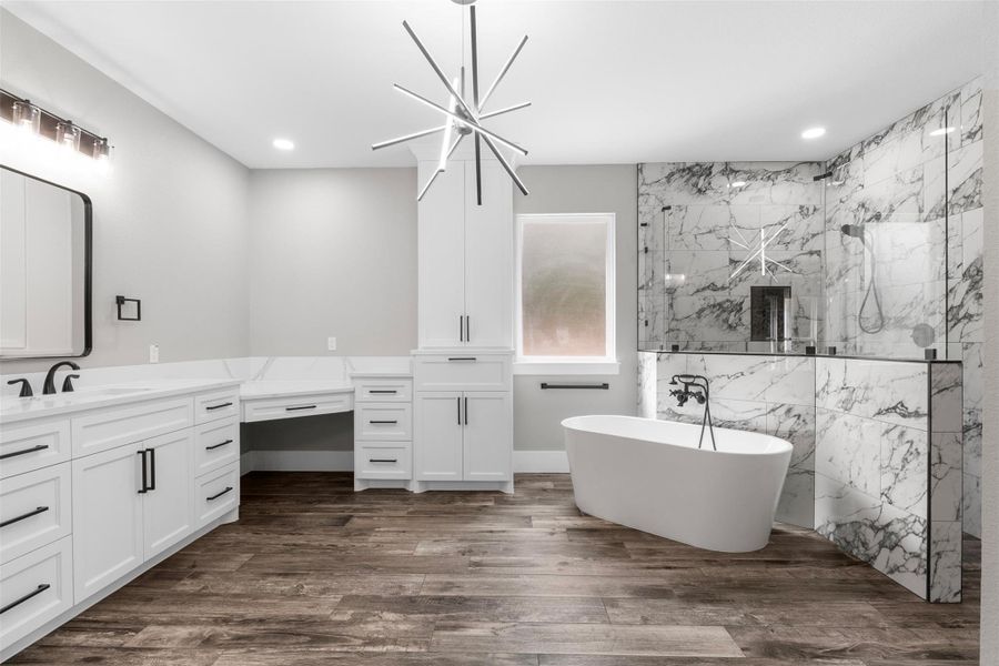 Luxurious bathroom featuring a sleek freestanding tub, elegant marble-tiled shower, and stylish modern lighting and ample cabinetry for a sophisticated retreat.