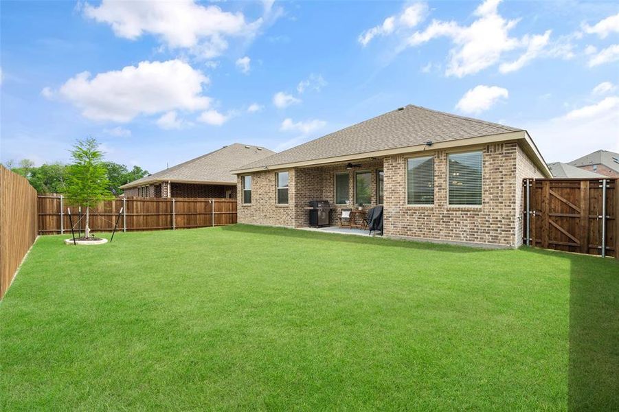 The property features a spacious backyard with a well-maintained lawn and a privacy fence