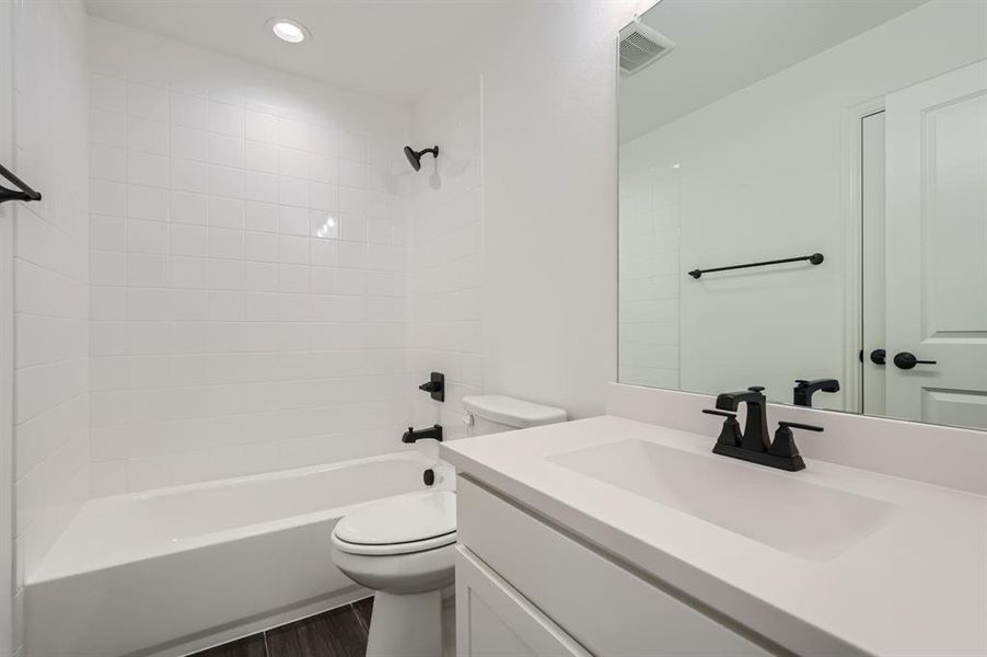 Full bathroom with hardwood / wood-style floors, toilet, vanity, and tiled shower / bath