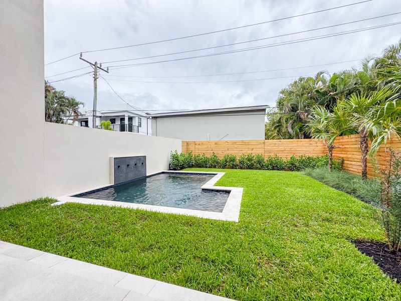 (as of April 8, 2026) view of spa pool and backyard from patio, clusia grows quickly and will be taller than fence by end of year