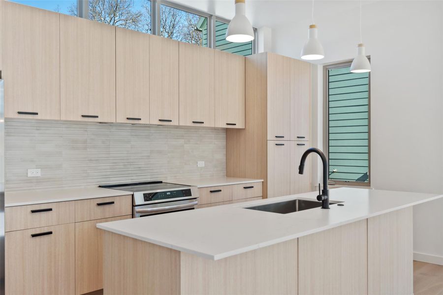 Kitchen featuring modern cabinets, a sink, stainless steel electric range, and light brown cabinetry