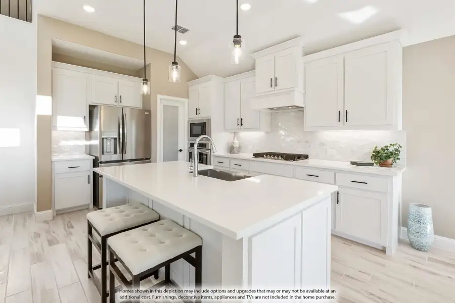 Kitchen with white cabinets, large center island, pendant lights, and stainless steel appliances on light wood floors