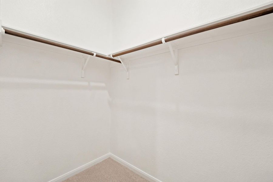 Ample built-in shelving and hanging rods maximize storage space inside the carpeted closet.