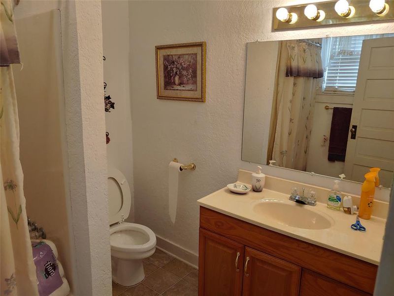 Bathroom featuring a vanity with a light-toned countertop, wood-finish cabinetry, and an integrated sink Bathroom featuring a vanity with a light-toned countertop, wood-finish cabinetry, and an integrated sink