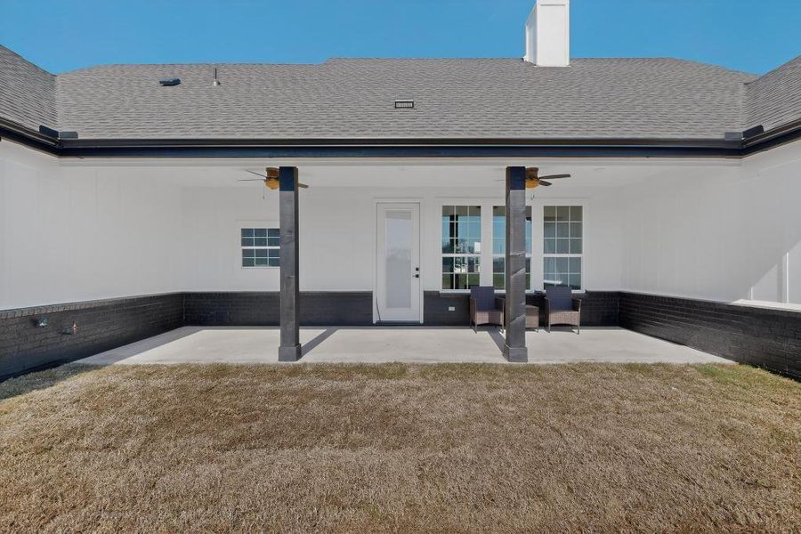 Rear view of house with ceiling fan, roof with shingles, a patio, and a yard