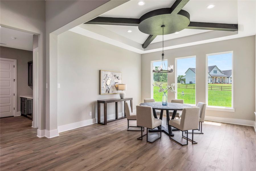 This spacious dining area features large windows, stylish light fixture, and a tray ceiling with exposed beams. This spacious dining area features large windows, stylish light fixture, and a tray ceiling with exposed beams.