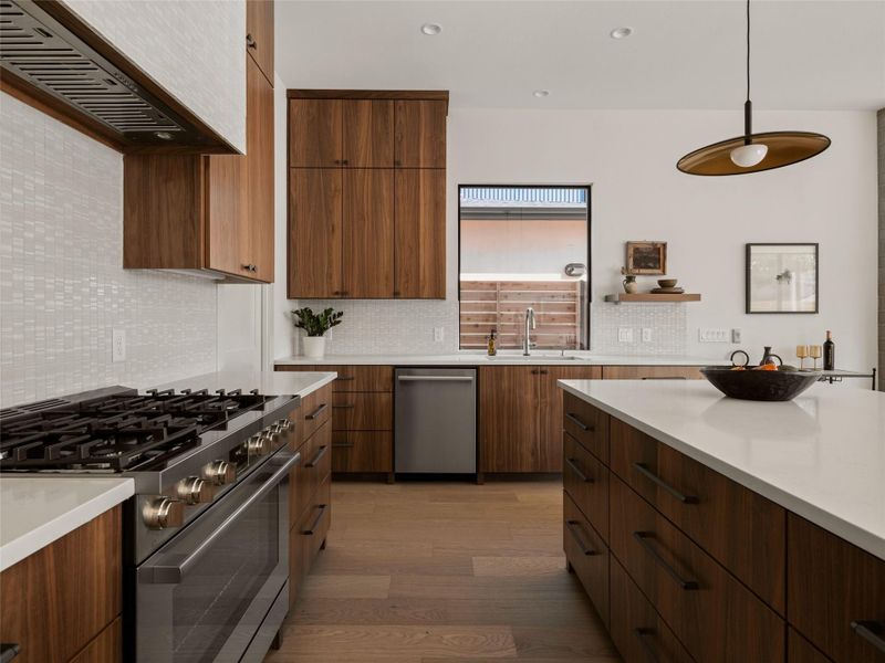 Kitchen with stainless steel appliances, wall chimney exhaust hood, tasteful backsplash, modern cabinets, and light wood-style flooring