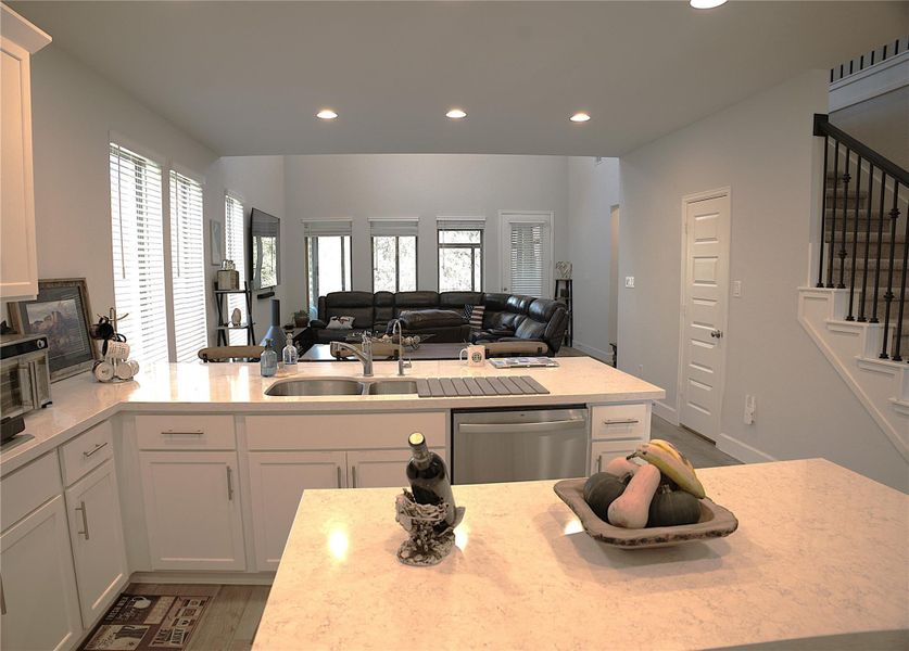 Kitchen featuring white cabinets, light wood-style floors, recessed lighting, stainless steel dishwasher, and light stone countertops Kitchen featuring white cabinets, light wood-style floors, recessed lighting, stainless steel dishwasher, and light stone countertops