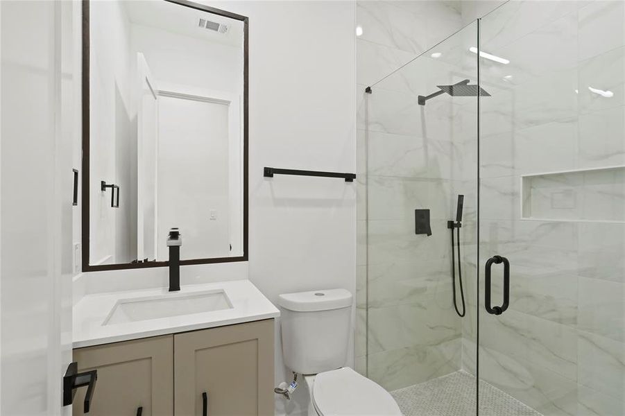 Bathroom with toilet, vanity, and an enclosed shower