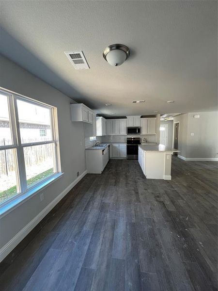 Kitchen with stove, dark hardwood / wood-style flooring, white cabinetry, and a kitchen island