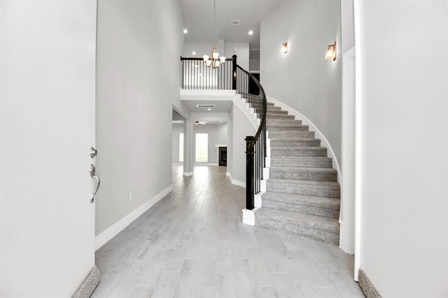 The majestic entryway allures with its high ceilings, embellished withsophisticated wood-look tile flooring and sleek oversized baseboards. Lift youreyes to a captivating sight of the open staircase, and follow the trail of naturallight pouring in through expansive windows as you journey to the family room,crafting an inviting and cozy ambiance. Sample photo of completed home with similar floor plan. Actual colors and selections may vary.