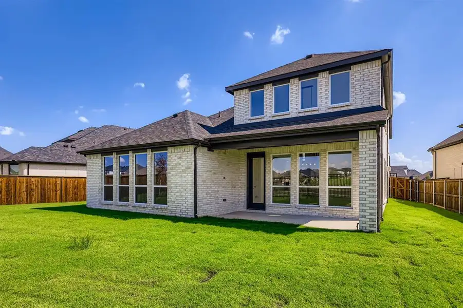 Back of property featuring brick siding, roof with shingles, and a fenced backyard