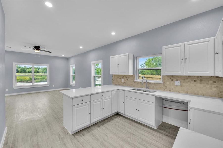 Kitchen featuring tasteful backsplash, recessed lighting, a peninsula, light countertops, and white cabinets