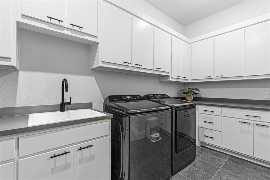 Laundry room with washing machine and dryer, cabinet space, and dark tile patterned floors