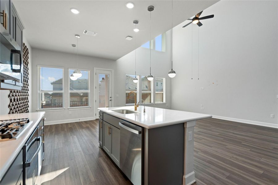 High ceilings and clean plank flooring frame a modern kitchen open to the living area.