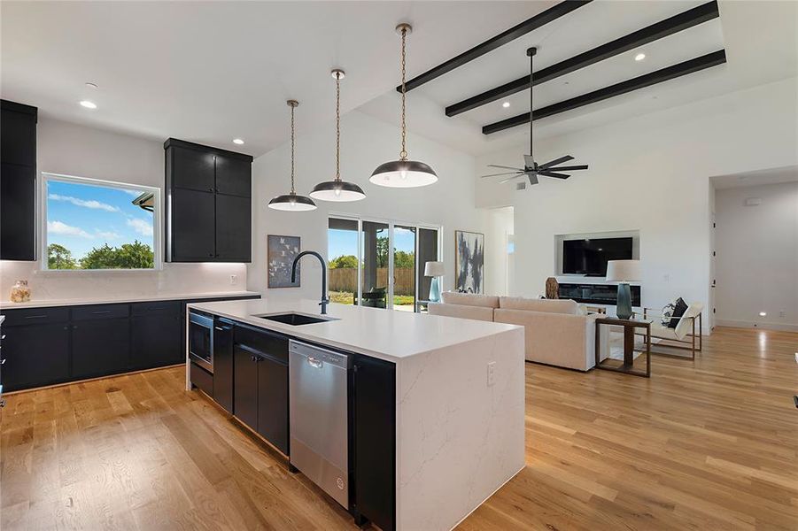 Kitchen with ceiling fan, light hardwood / wood-style flooring, a center island with sink, stainless steel dishwasher, and sink