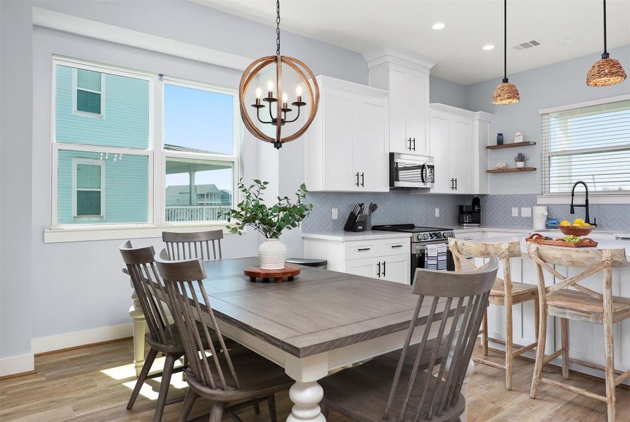 The dining room offers plenty of room for meals with family and friends. With a chic light fixture above and scattered windows framing beautiful Gulf views, every meal feels special.