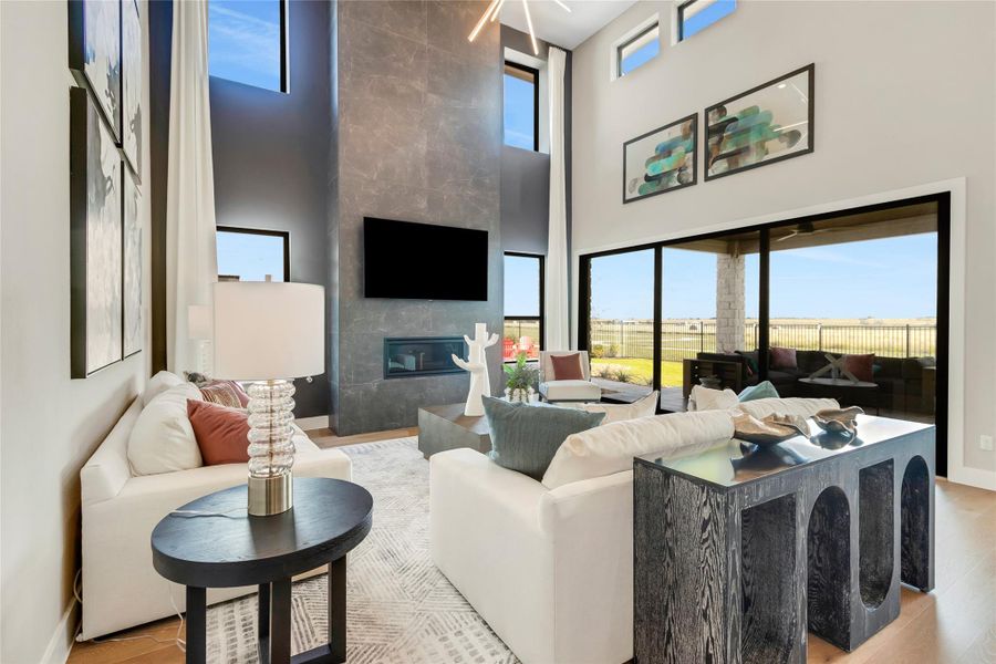 Living room featuring a fireplace, wood finished floors, and a high ceiling Living room featuring a fireplace, wood finished floors, and a high ceiling