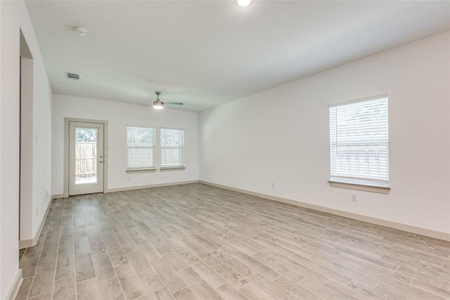 Living room features a ceiling fan, tile wood-like flooring and lots of natural light.