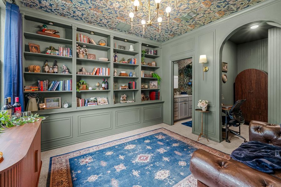 Living area with arched walkways, light carpet, suspended lighting, a decorative wall, and crown molding