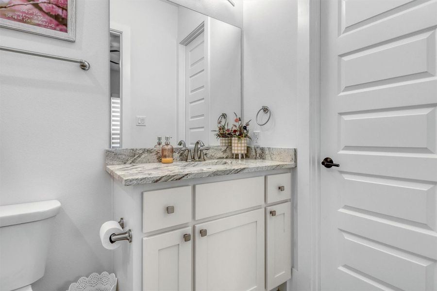 Full secondary ensuite bathroom on the first floor has white vanity, granite countertops, tile flooring, and a shower/tub combination.
