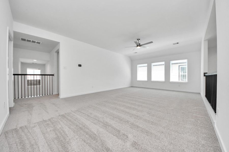 Discover a haven of leisure in this fantastic game room! Whether you're seeking a casual hangout or an adult gaming retreat, this space has it all. Enjoy the luxurious feel of plush carpet underfoot, the expansive ambiance of high ceilings, custom paint that adds a touch of personality, and windows that flood the room with refreshing natural light. Sample photo of completed home with similar floor plan. Actual colors and selections may vary.