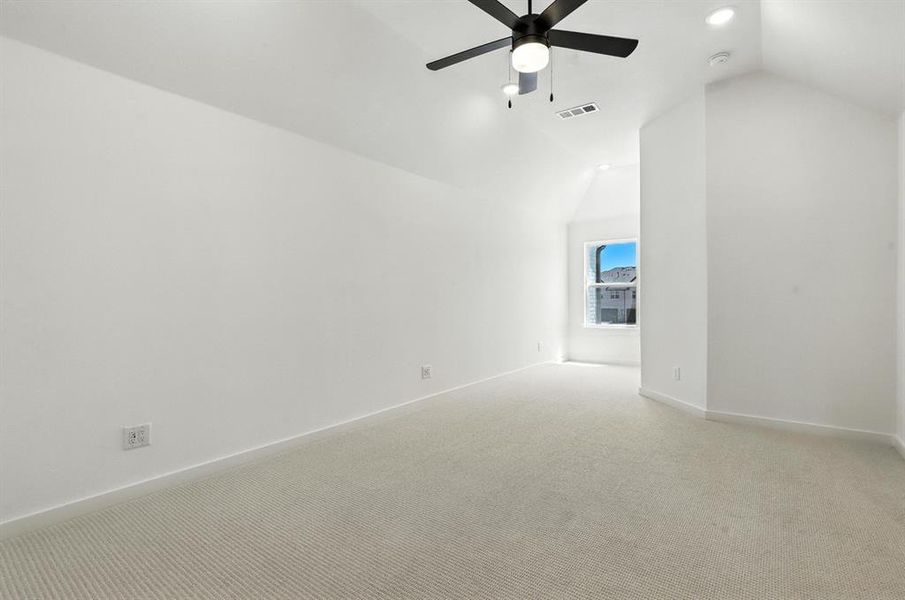 Carpeted empty room featuring lofted ceiling and a ceiling fan Carpeted empty room featuring lofted ceiling and a ceiling fan