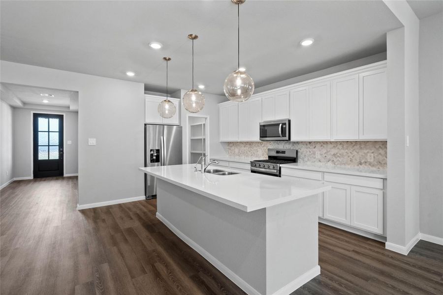 The extended quartz countertop creates a convenient breakfast bar, providing a casual and inviting space where stools can be added for quick meals or long conversations.