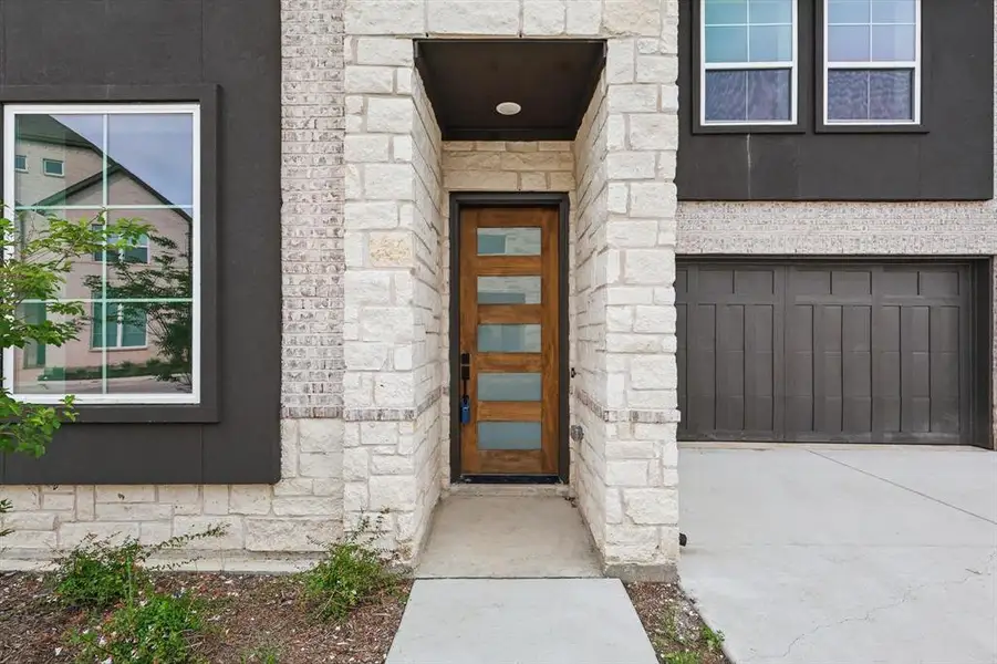 View of exterior entry featuring stone siding and concrete driveway