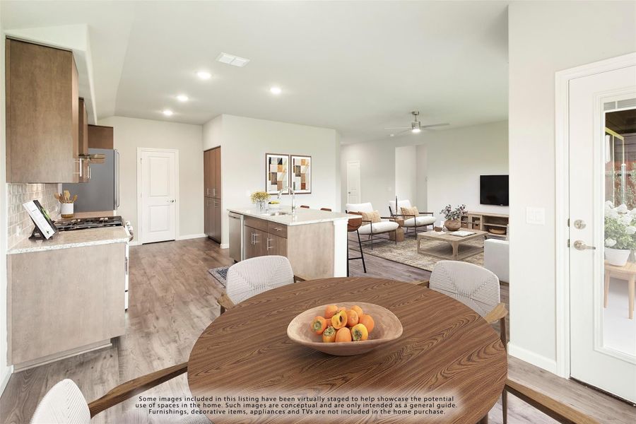 Open-plan dining area with round wood table, kitchen island, and living room with hardwood floors