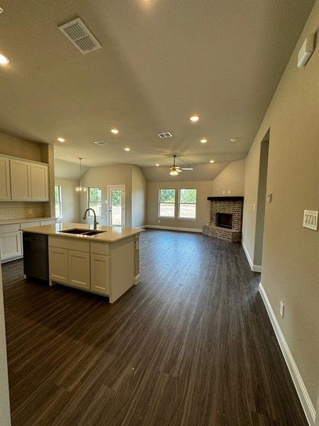 Kitchen with a kitchen island with sink, ceiling fan with notable chandelier, sink, stainless steel dishwasher, and white cabinetry