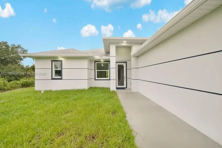 Modern exterior featuring stucco finish with horizontal trim detailing, a recessed covered entryway, and a concrete walkway