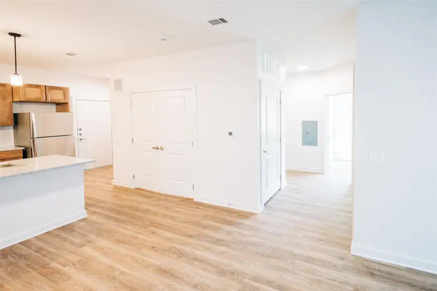 Kitchen featuring freestanding refrigerator, light wood finished floors, decorative light fixtures, and brown cabinetry