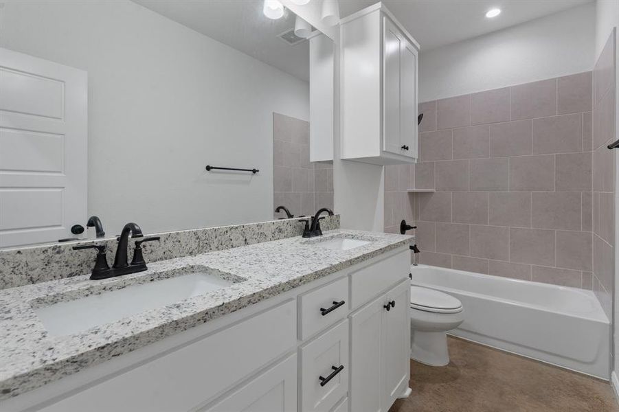 Full bathroom with toilet, tiled shower / bath combo, and vanity