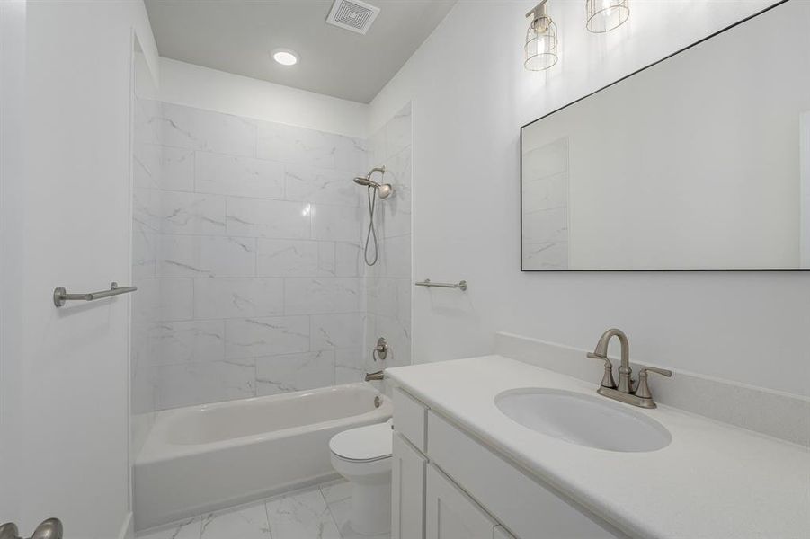 Full bathroom featuring tiled shower / bath, vanity, and toilet