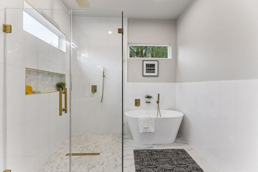 A well-appointed bath features a spacious glass-enclosed shower and a freestanding soaking tub for ultimate relaxation.