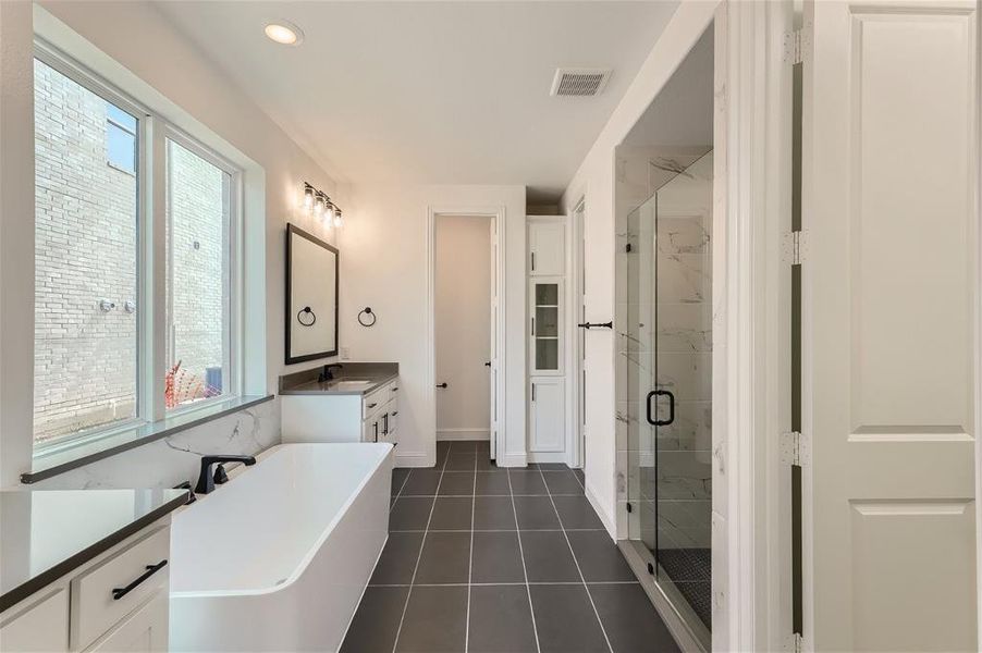 Bathroom with shower with separate bathtub, vanity, and tile floors