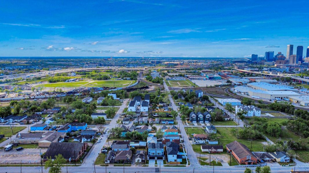 This aerial photo showcases a residential neighborhood with a mix of traditional and modern homes, ample green spaces, and convenient proximity to a city skyline, offering a blend of suburban tranquility and urban accessibility.