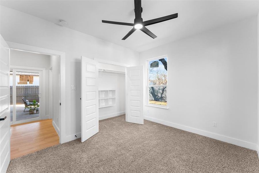 Unfurnished bedroom featuring light colored carpet, a closet, and a ceiling fan