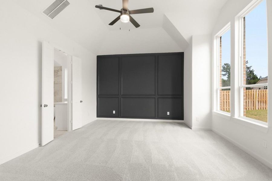 Extended primary bedroom with bold accent wall and vaulted ceiling!
