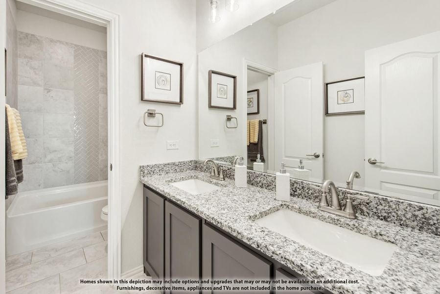 Bathroom with double granite vanity, gray cabinets, large mirror, and tiled shower-tub combo