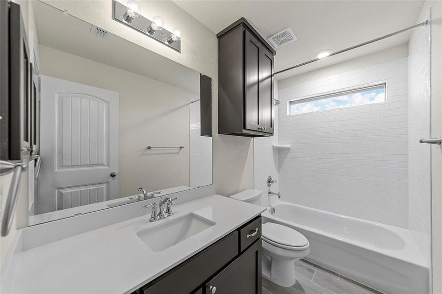 Bathroom featuring washtub / shower combination, vanity, and wood finish floors Bathroom featuring washtub / shower combination, vanity, and wood finish floors