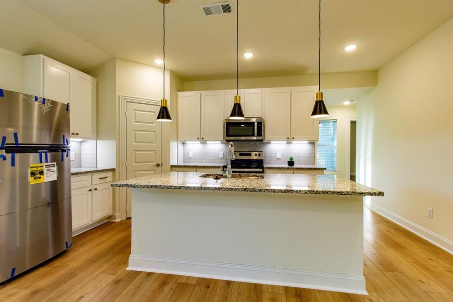 Kitchen with appliances with stainless steel finishes, white cabinetry, tasteful backsplash, light stone countertops, and recessed lighting Kitchen with appliances with stainless steel finishes, white cabinetry, tasteful backsplash, light stone countertops, and recessed lighting