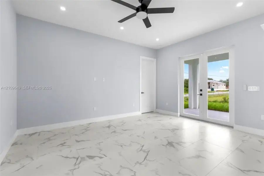 Large-format stone-patterned tile flooring, recessed ceiling lighting, matte black ceiling fan, and full-lite glass French doors
