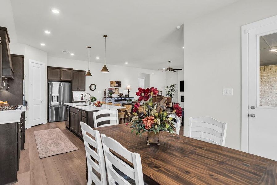 Dining/Breakfast room featuring wood-finish flooring, white walls, and backyard views opens to Kitchen and Living rooms