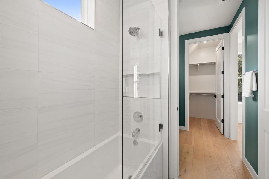 Bathroom with wood-type flooring and tiled shower / bath combo