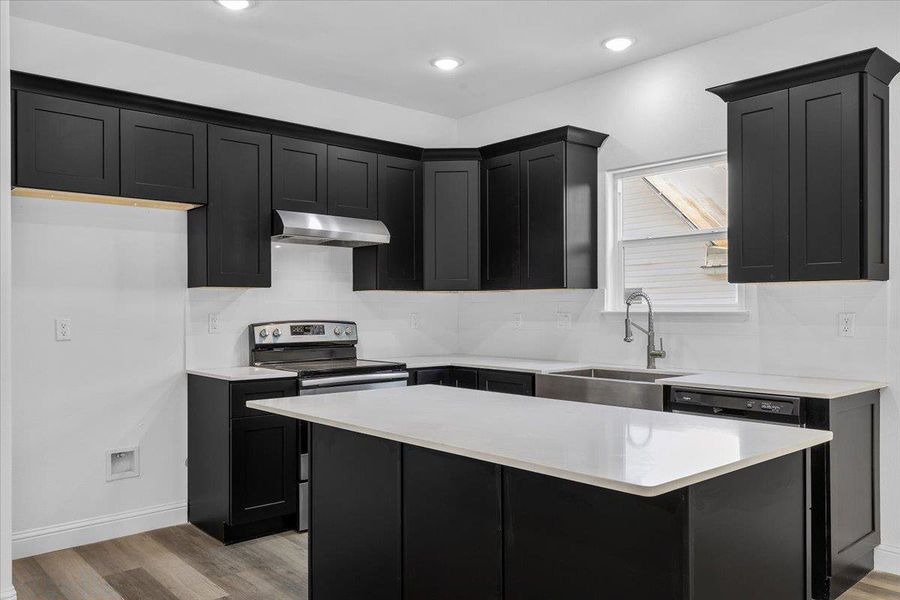 Bold dark cabinetry contrasts beautifully with pristine countertops and modern flooring in this updated kitchen. Bold dark cabinetry contrasts beautifully with pristine countertops and modern flooring in this updated kitchen.