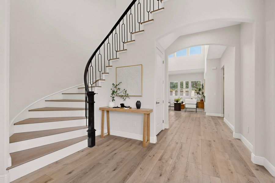 An elegant curved staircase anchors this welcoming entry featuring wide plank wood flooring.