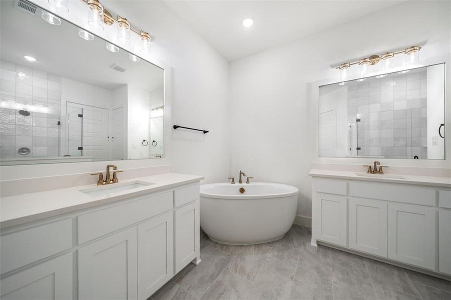 Bathroom with a shower stall, two vanities, a freestanding bath, and recessed lighting